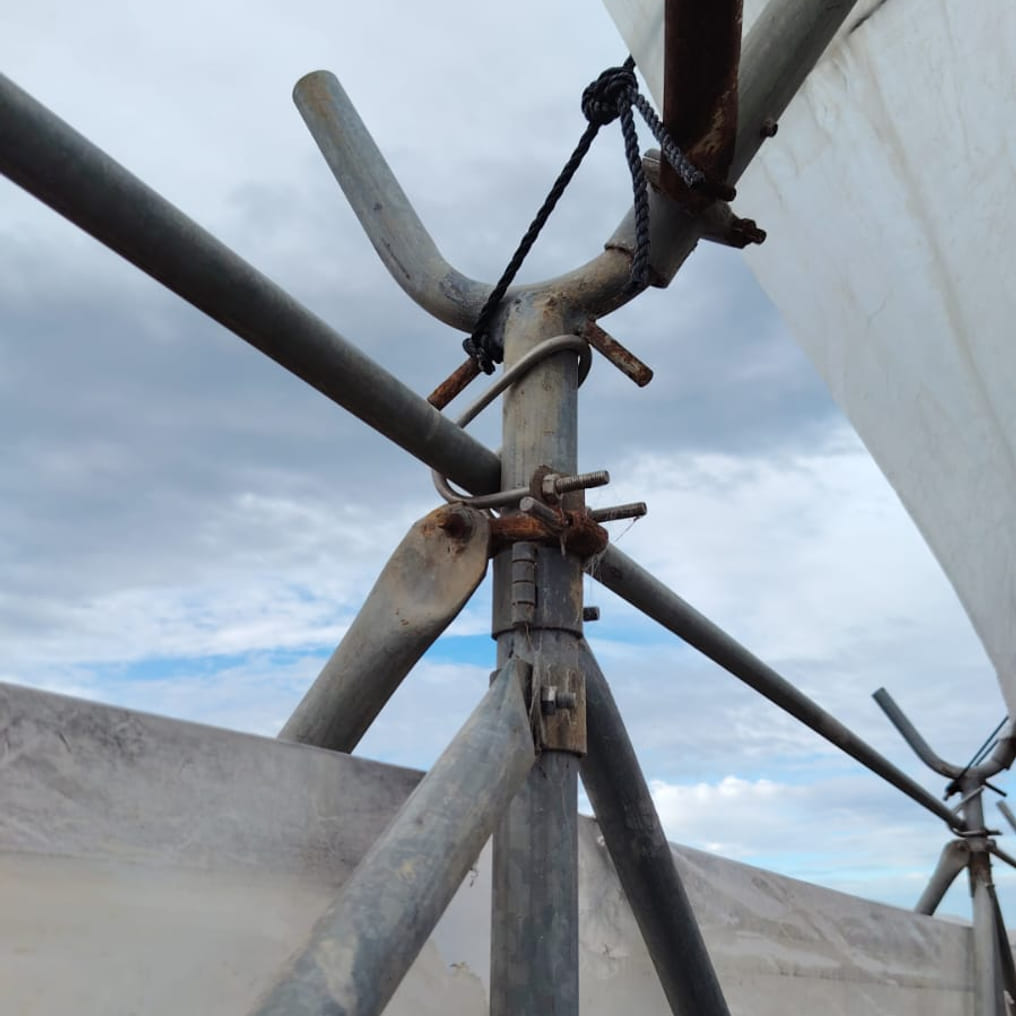 Polytunnel scaffold joint – galvanised pipe clamp with a tensioning rope tie, the kind of fitting Afrishore supplies for tunnel construction, trellising and orchard tensioning across the Garden Route.